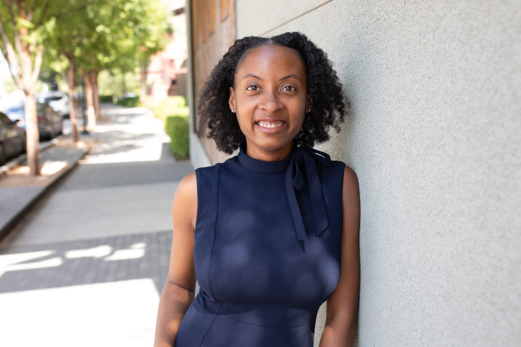 Jeanine Thomas, author of this page, leaning against a brick wall of a coffee shop