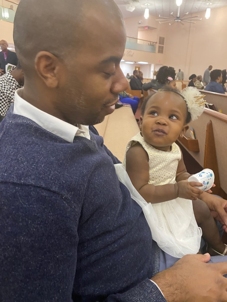 A man and a young child sitting together in a church setting, sharing a moment of connection and affection.